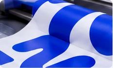 Rollo blanco con gráficos azules junto a los rodillos de una impresora
